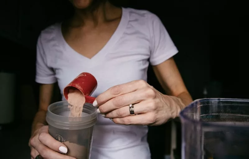 Mulher colocando whey protein em sua shakeira